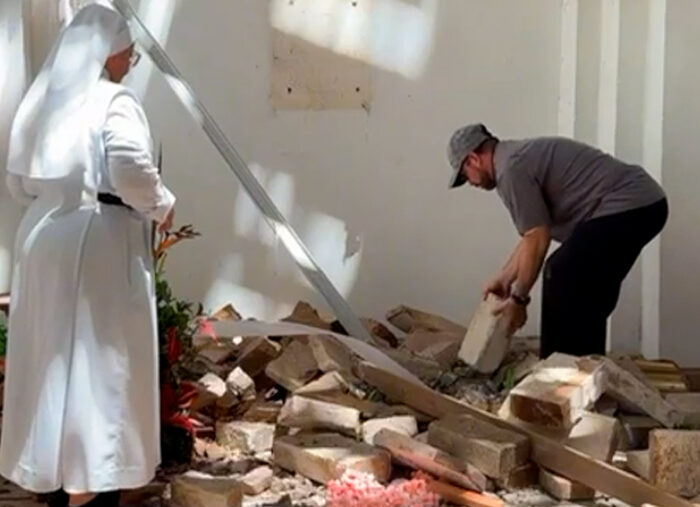 Con reverencia, sacerdote y religiosa colombianos recogen hostias que el sismo esparció por el suelo